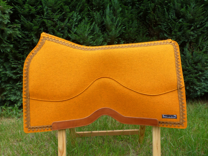 Leuchtend orangefarbener, reiner Wollfilz, verziert mit bronzefarbenen Posamenten und braunem Leder. Dieses Westernpad hat das Zeug zur Show- und Turnierausrüstung.